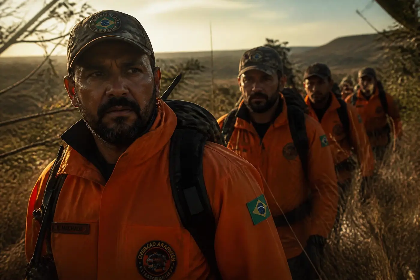 Homens em jaqueta laranja dos Legendários caminhando na montanha ao amanhecer